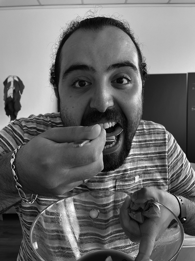 Ahmad Alshikhobeid mit Salatschüssel in der Hand und Gabel im Mund