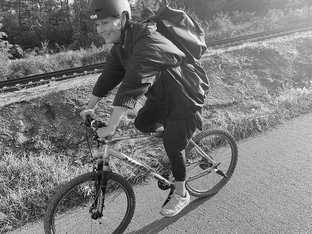 Pia auf einem Fahrrad mit Fahrradhelm und Rucksack